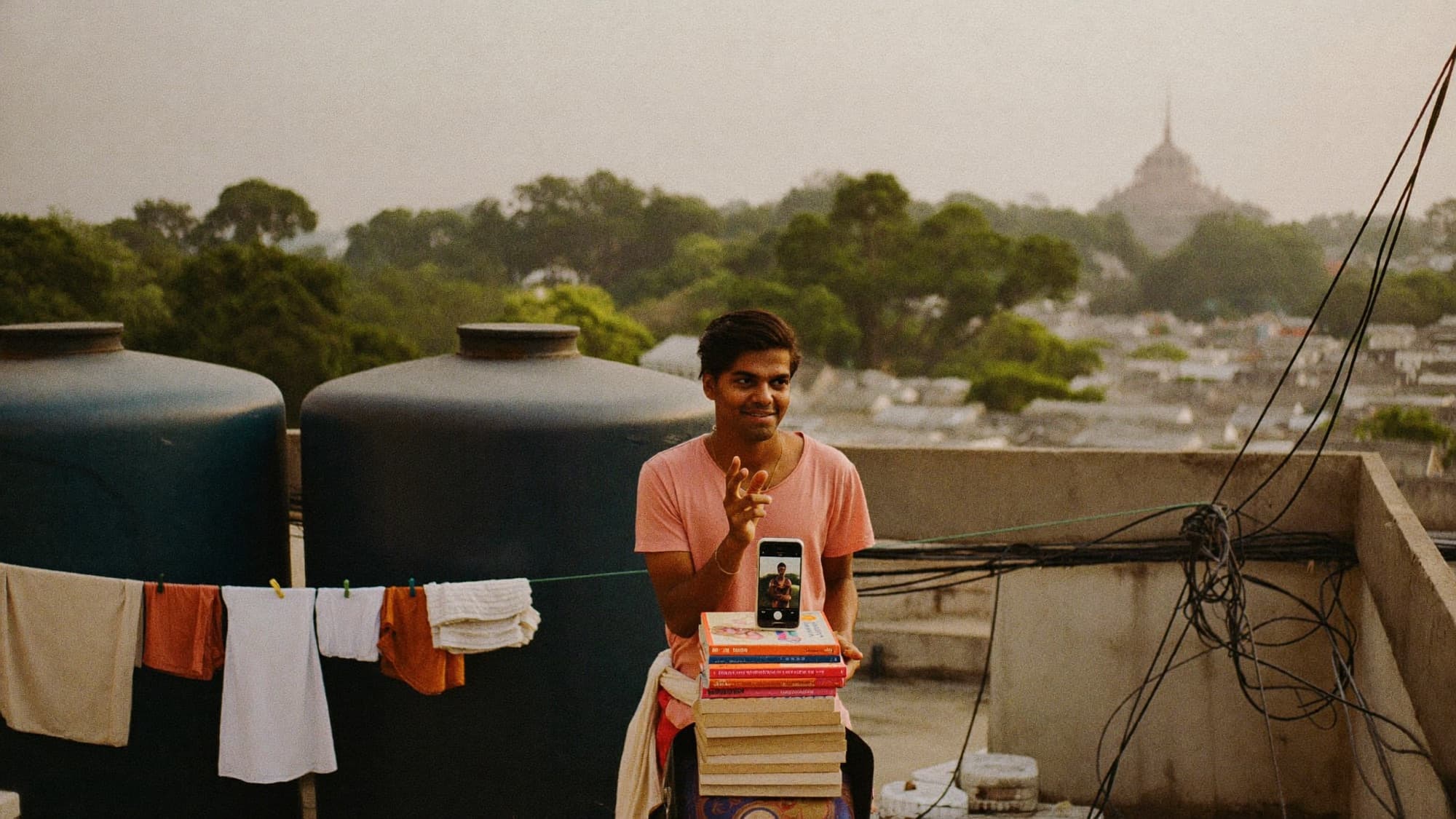 A creator records a video with his phone on a rooftop