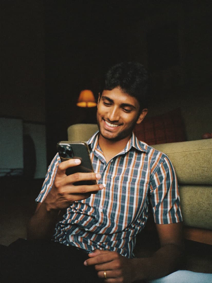 A viewer smiles while watching creator content on his phone at home